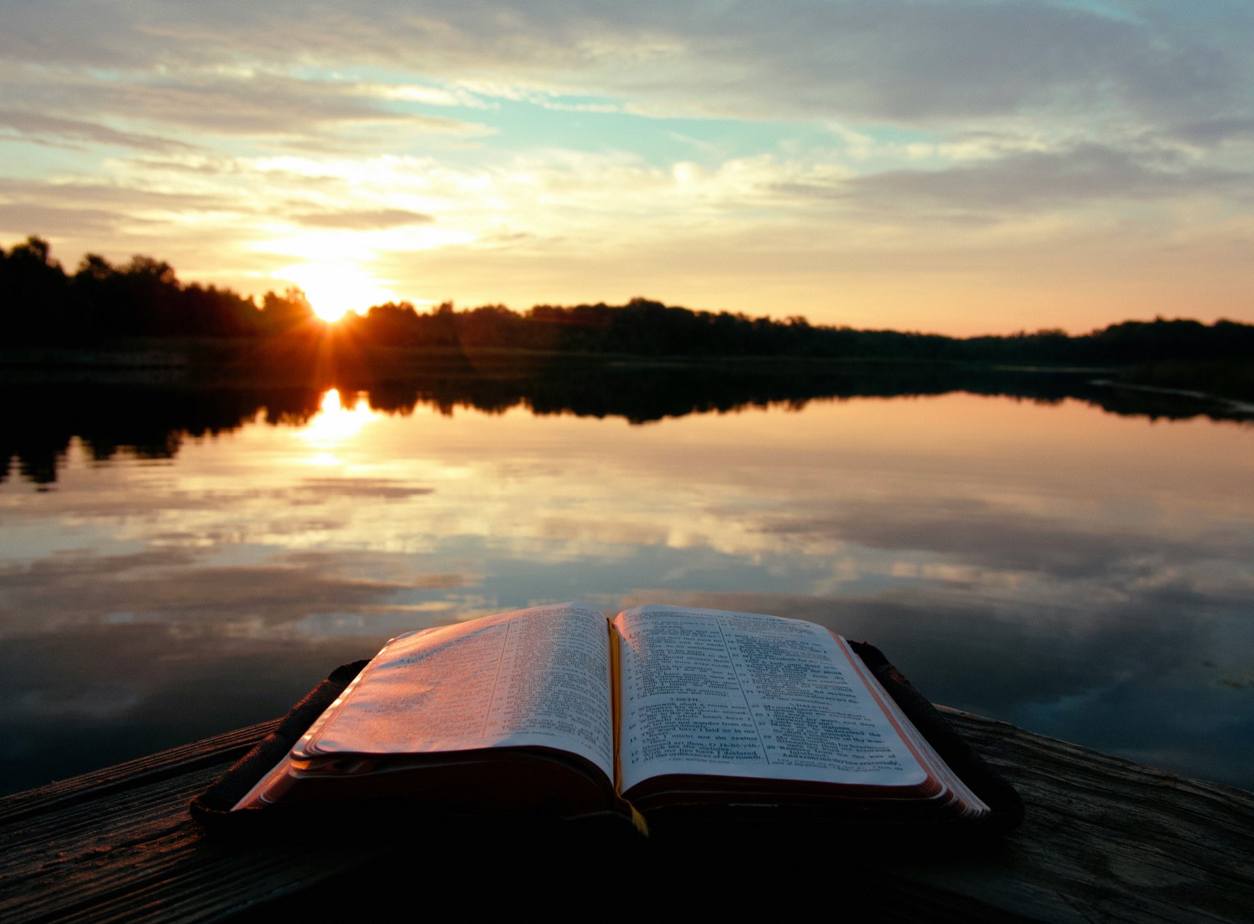 An open Bible lit by warm sunset light.